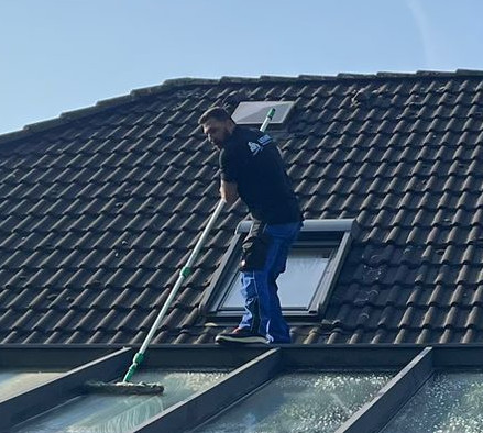 Ein Mitarbeiter reinigt eine Glasüberdachung